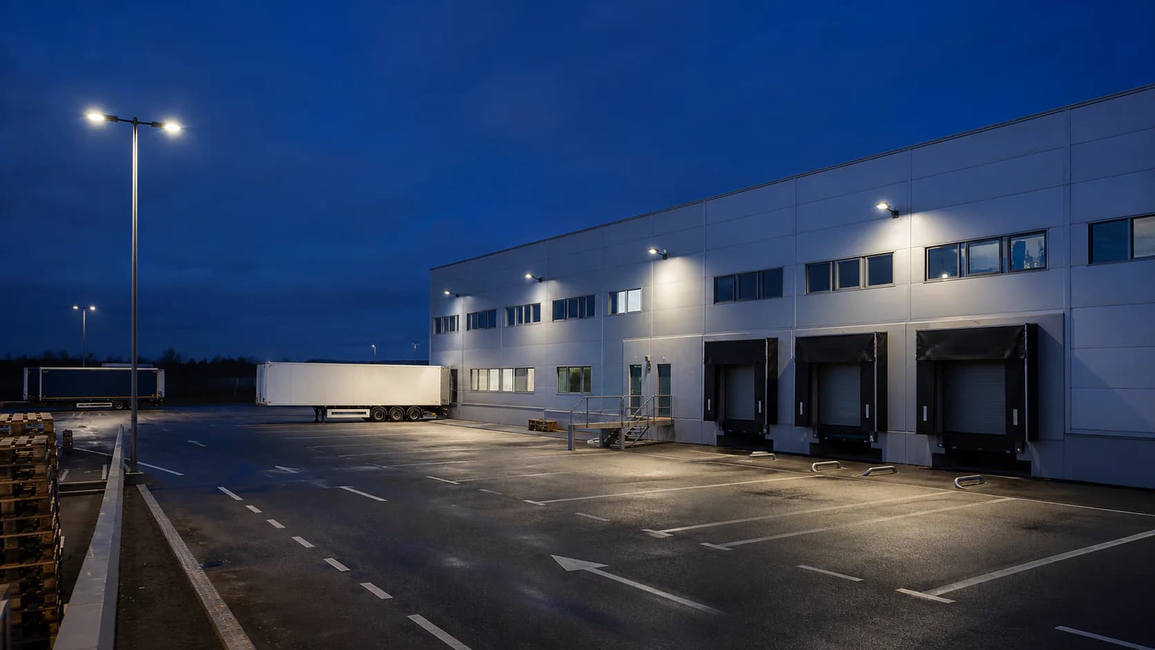 Dusk view of a working commercial yard with visible pole positions, traffic routes and site boundary; balanced exposure, no artificial lens flare.